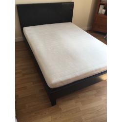 Dark brown double bed with mattress.